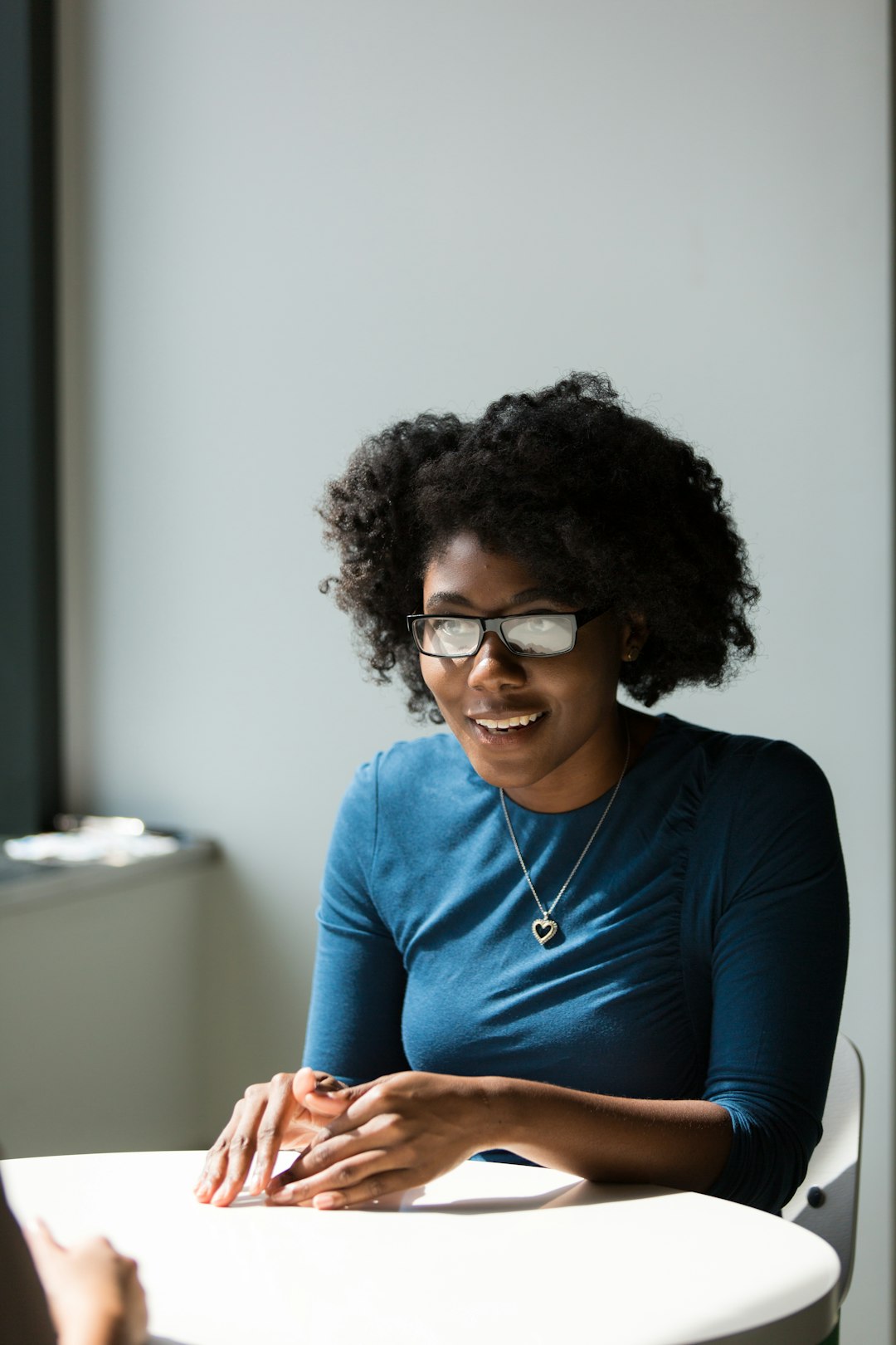 smiling-woman-wearing-blue-shirt-sitting-beside-table-wktu9vlr5jm
